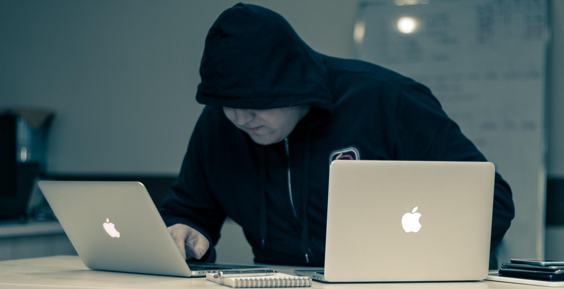 man in black hoodie using macbook